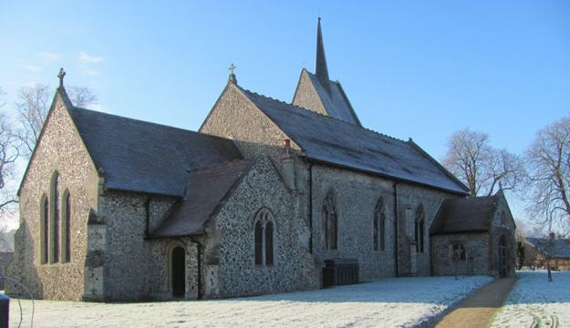 St Leonards Church in Mundford, a flint stone parish church with a tall spire pictured on a clear winter morning