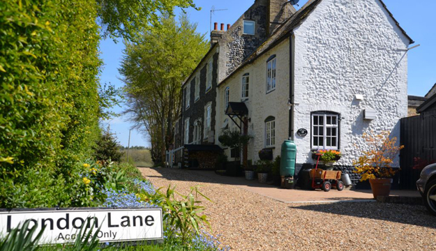 Whitewashed cottages on London Lane in Mundford, beside a road sign reading London Lane Access Only